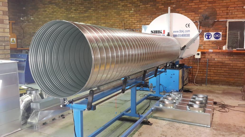 Spiral duct machine rolling full-length ducting in the workshop